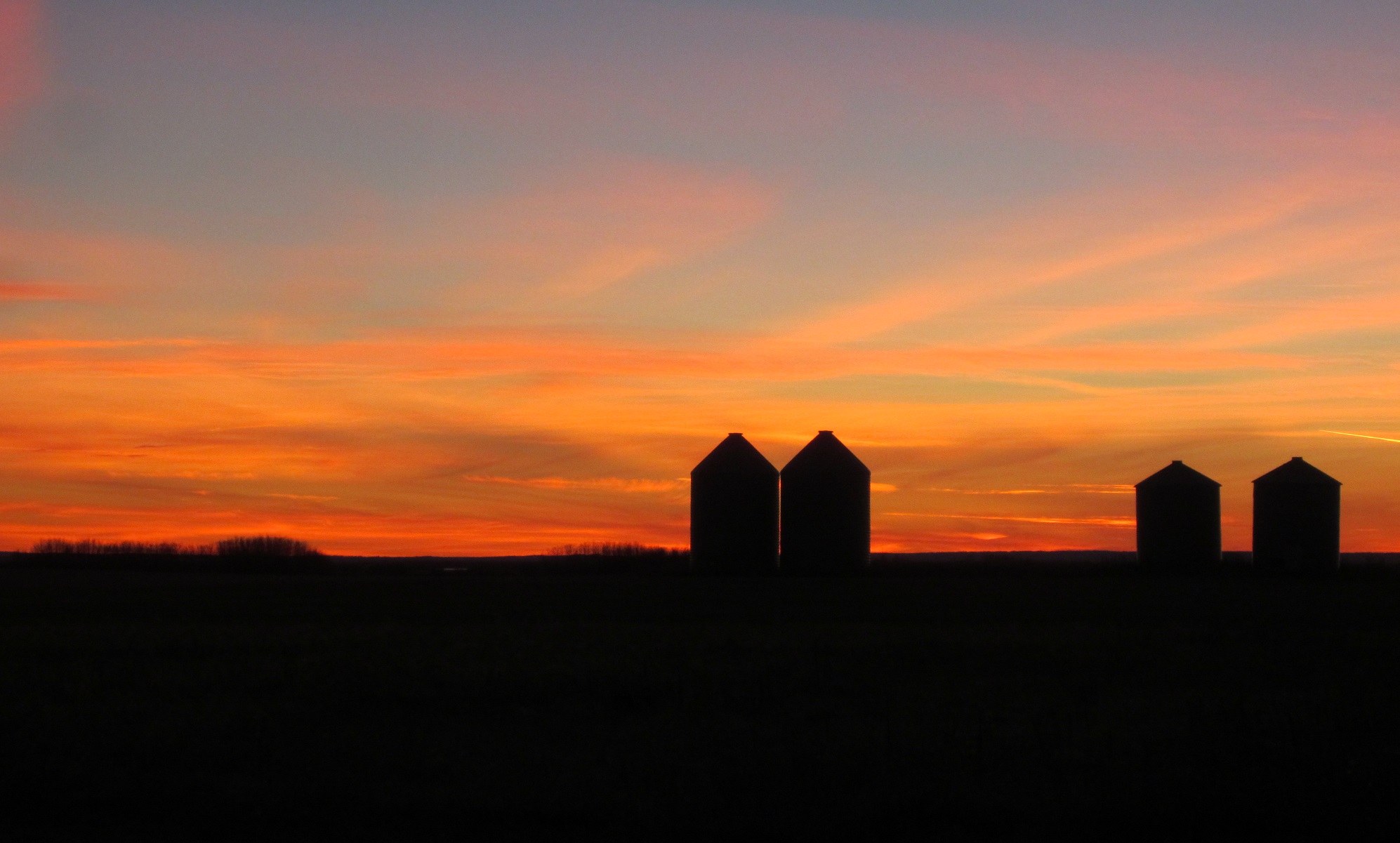 4 prairie bins during a sunset.